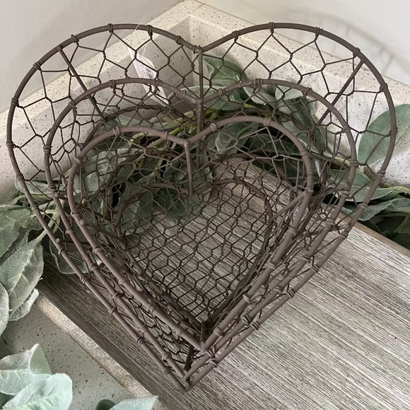 Decorative metal heart-shaped basket with greenery on a wooden surface